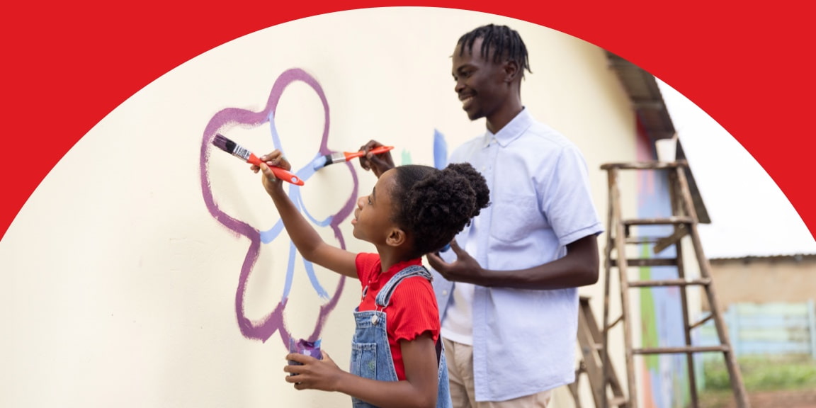 A UNICEF caregiver painting a flower with a young girl on a wall.