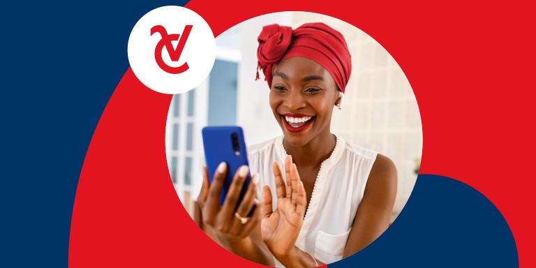 A happy young African woman wearing a vibrant headscarf smiles as she looks at her cell phone.
