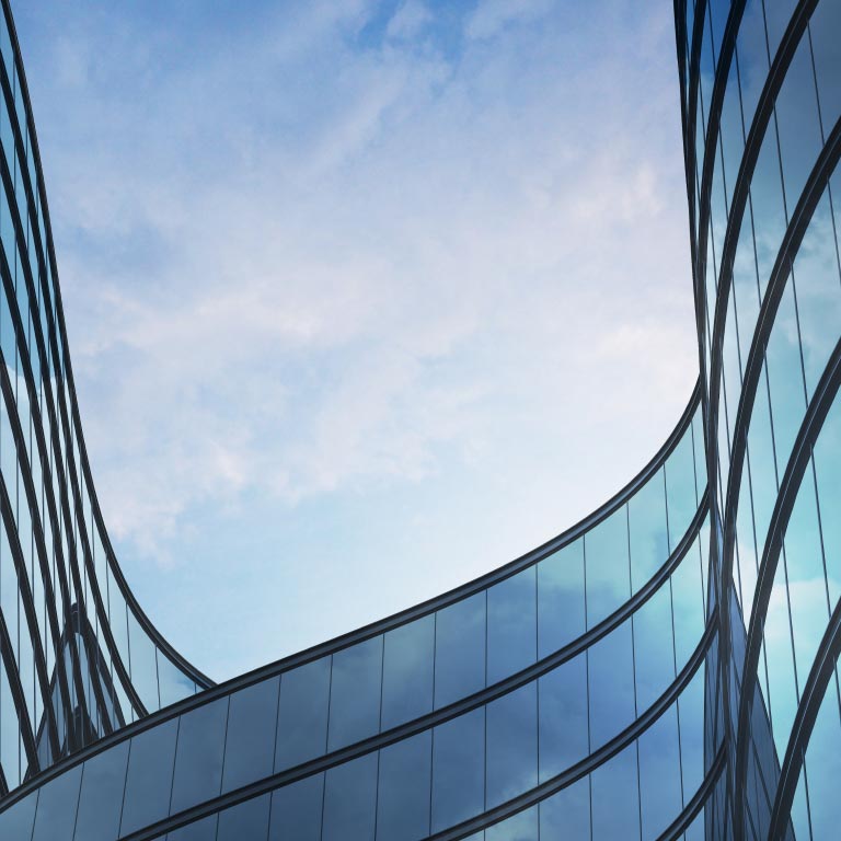 Low-angle perspective of a high-rise building with glass and dark steel.