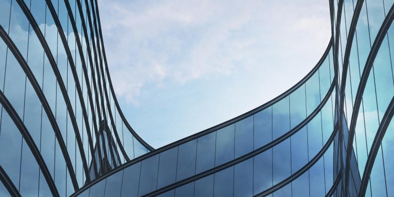 Low-angle perspective of a high-rise building with glass and dark steel.