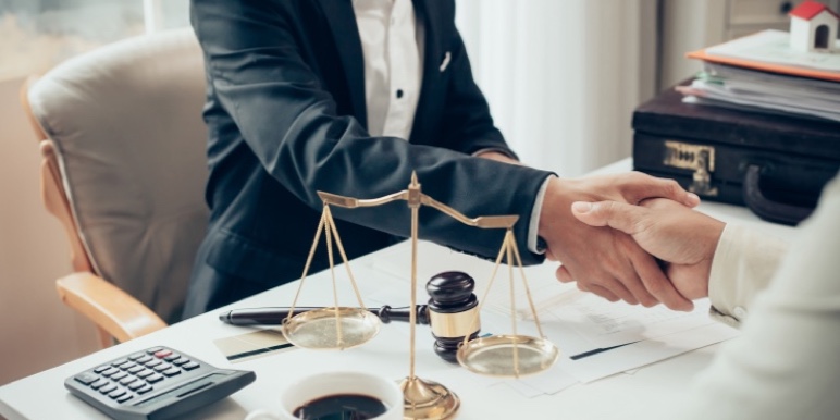 A client shaking hands with their nominated professional executor beside a gavel and balance scale representing impartiality and legal expertise.