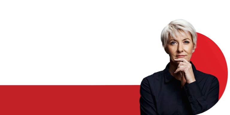 Mature, woman with short platinum hair and wearing a black shirt standing in a confident power pose.