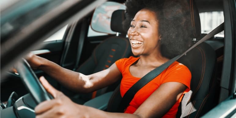 A young lady smiling while driving her car – she has just earned a Safe Dayz by travelling safely to and from her destination.