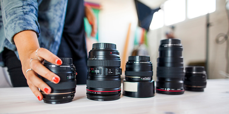 A female amateur photographer placing all her insured and expensive camera lenses on a table.