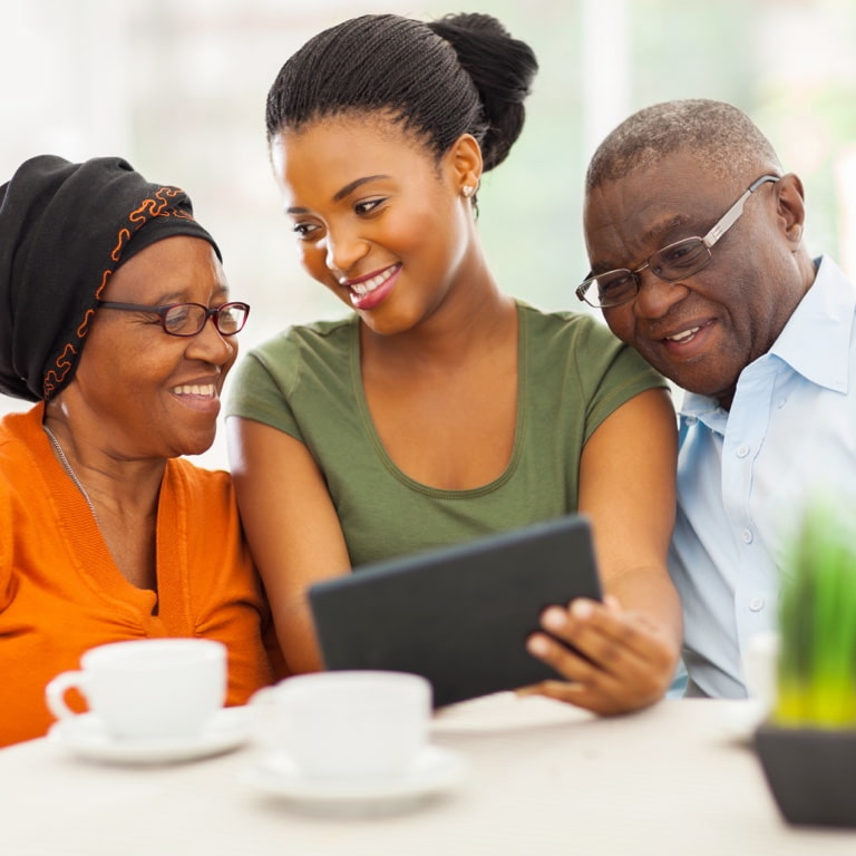 A woman in the middle of her parents showing them how to do an online will with Momentum.