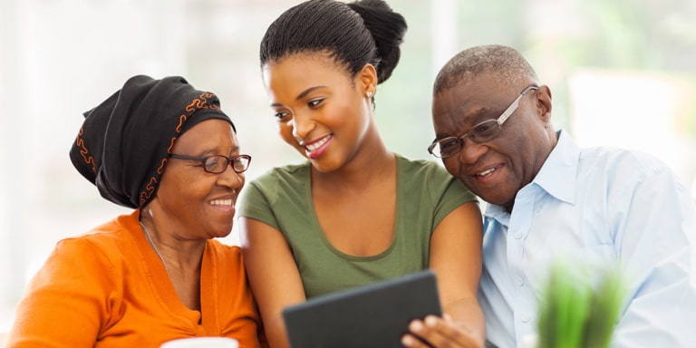 A woman in the middle of her parents showing them how to do an online will with Momentum.