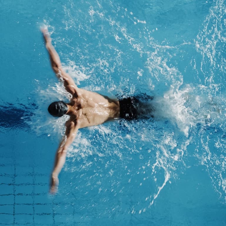 A man swimming at his maximum performance in an Olympic-sized swimming pool during a competitive race. 