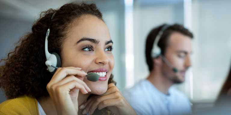 Two people in a call centre with head sets assisting members with their employee benefits.