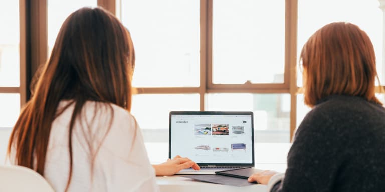 Two ladies working on a laptop together.
