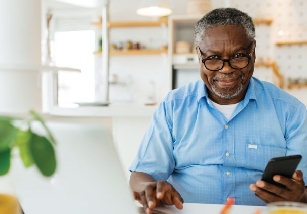 A smiling middle-aged man updating his beneficiaries on his phone.