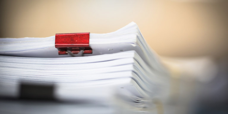 A thick stack of white papers with a blurred background.