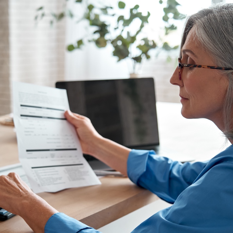 A middle aged lady, sitting at a desk, reviewing her retirement benefit statement.