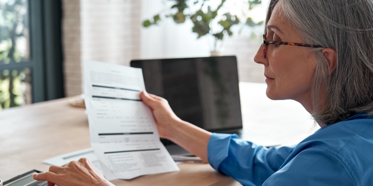 A middle-aged white woman reading a letter from her financial services provider about the latest regulation changes on her pension fund.