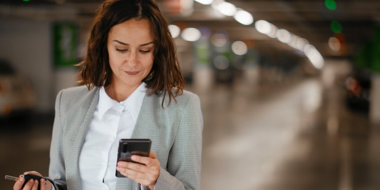 A woman walks and looks at her cell phone at the same time.